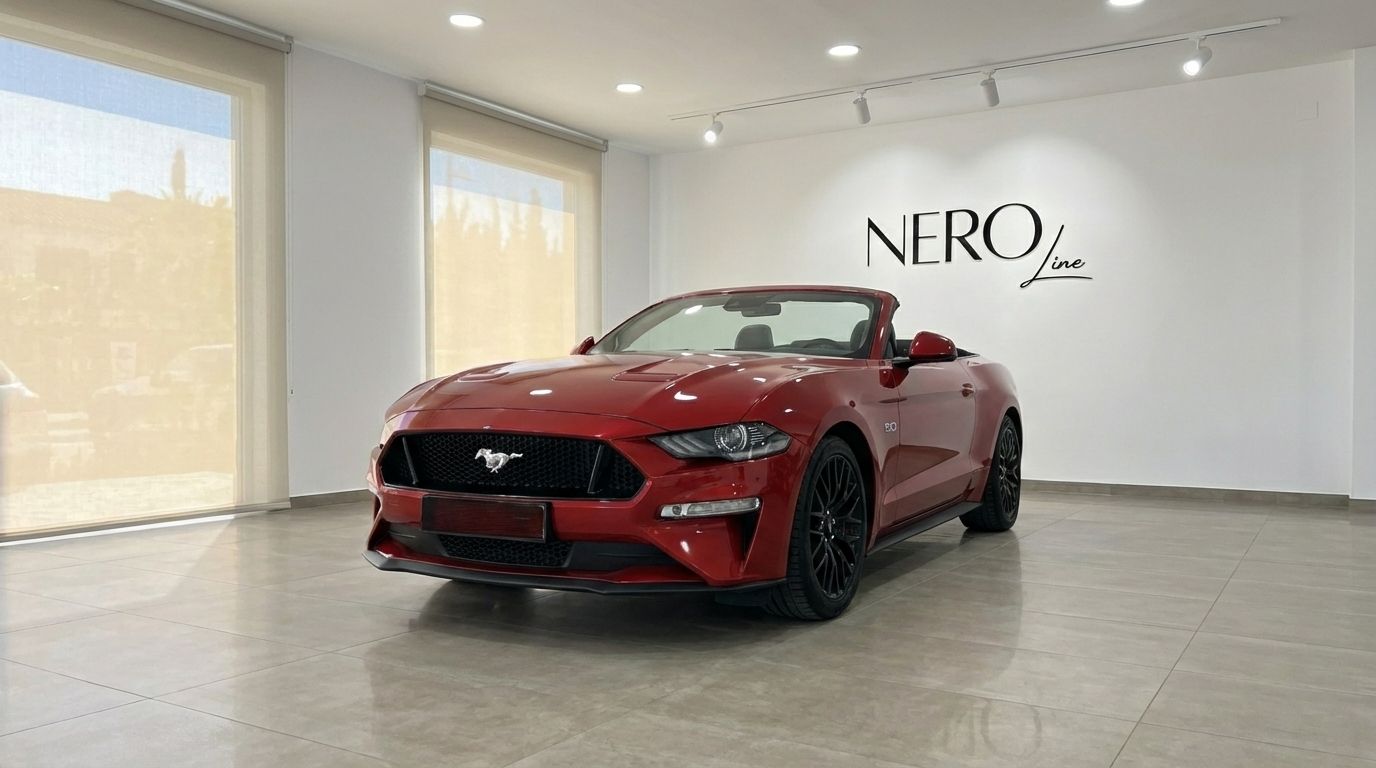 The racing red 2022 Ford Mustang GT Cabrio is showcased from a front three-quarter view with its top down in a bright Alicante showroom.