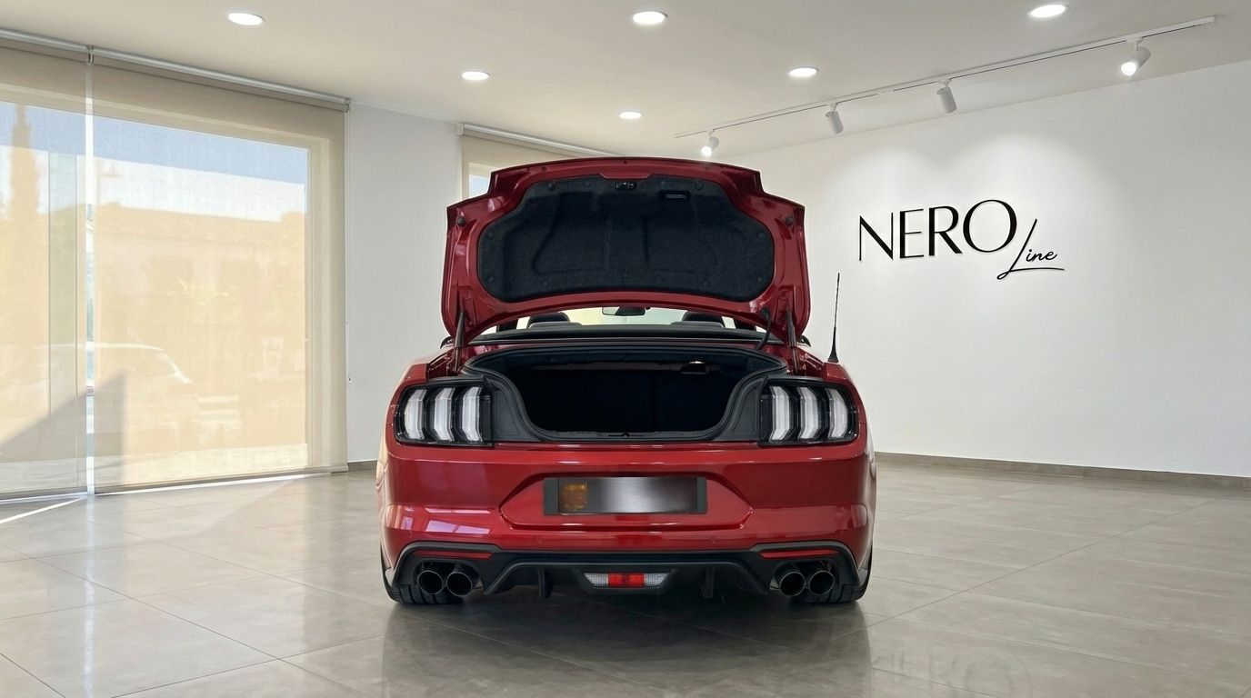 The rear view of a red 2022 Ford Mustang GT Cabrio with its trunk open, parked in a showroom in Alicante.