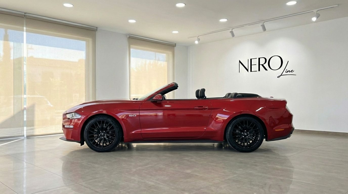 The racing red 2022 Ford Mustang GT Cabrio is parked with its top down, showcasing its sleek side profile in Alicante.