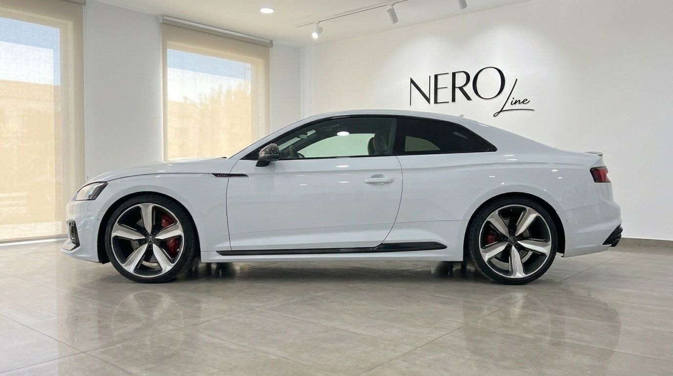 The white Audi RS5 coupe is shown in a side profile view, highlighting its sleek design and wheels in Alicante.