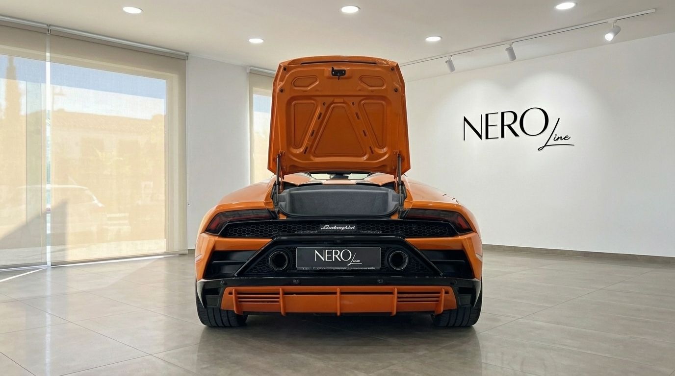 The vibrant orange Lamborghini Huracan Evo Spyder is captured from the rear, showcasing its open engine bay in a Malaga showroom.