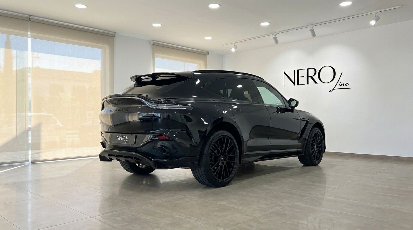 El elegante SUV de lujo Aston Martin DBX 707 negro se exhibe desde un ángulo trasero tres cuartos dentro de un moderno showroom en Ibiza.
