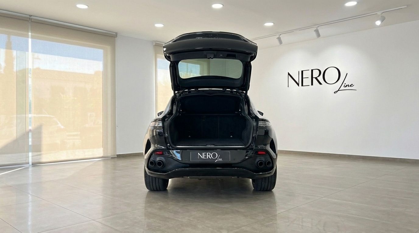 El SUV negro Aston Martin DBX 707 se muestra desde la parte trasera con el maletero abierto, aparcado en un concesionario en Ibiza.