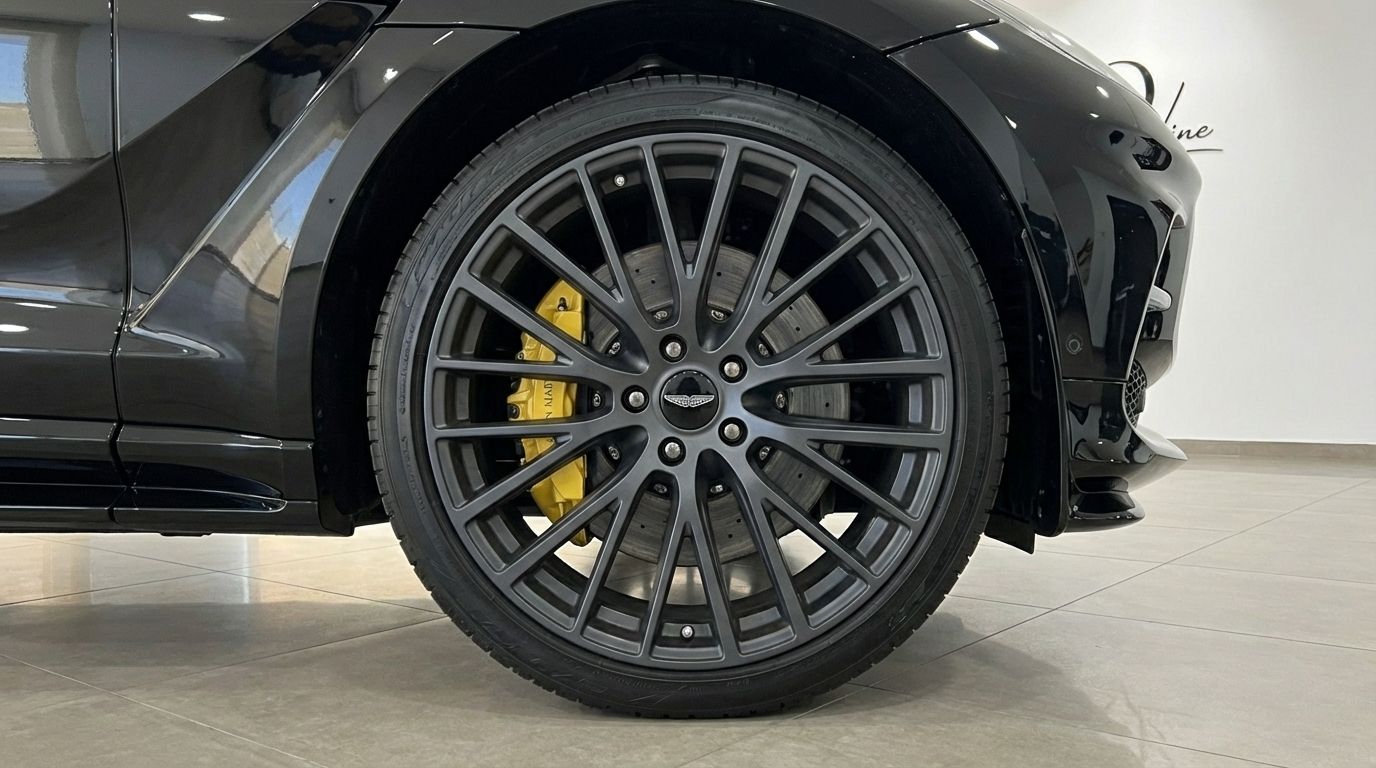 La rueda delantera del Aston Martin DBX en Madrid, con una llanta multirradio gris oscuro y una pinza de freno amarilla vibrante.