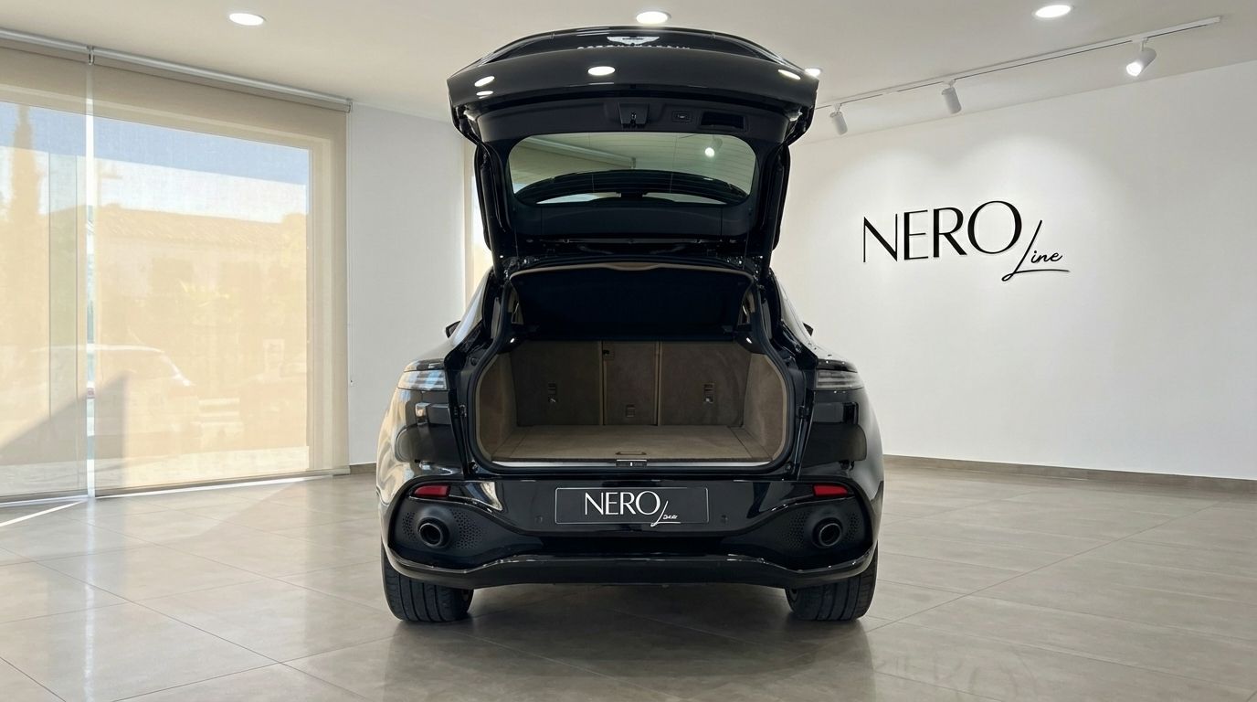 El Aston Martin DBX negro de 2025 se muestra desde la parte trasera con el maletero abierto, revelando el espacioso área de carga en Madrid.