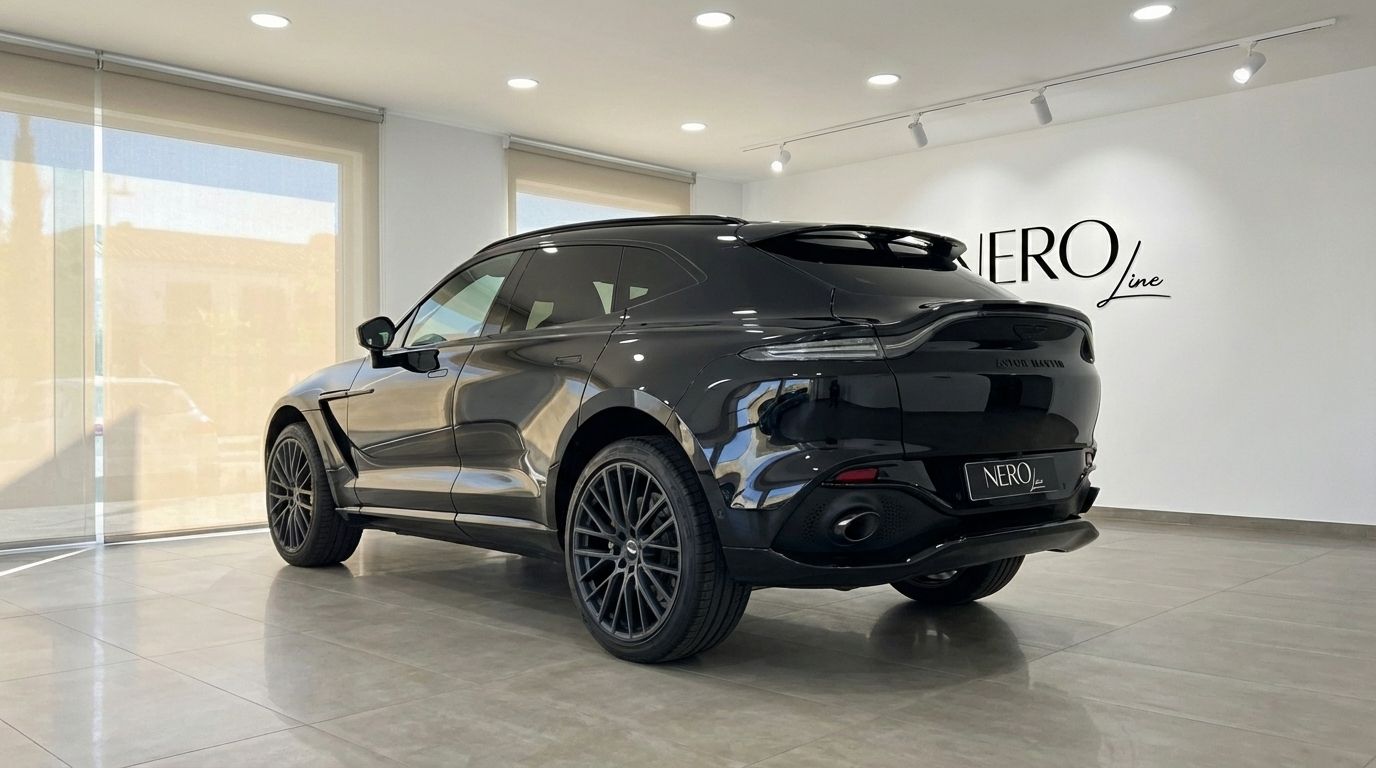 El Aston Martin DBX negro de 2025 se exhibe desde una vista trasera tres cuartos en un lujoso concesionario en Madrid.