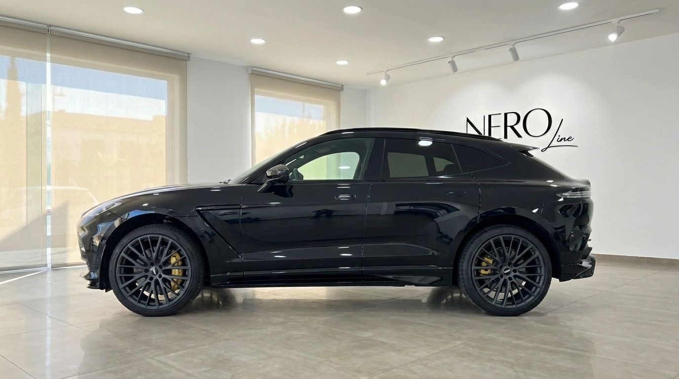 El SUV de lujo Aston Martin DBX 2025 negro se muestra desde su elegante perfil lateral, estacionado en Madrid.