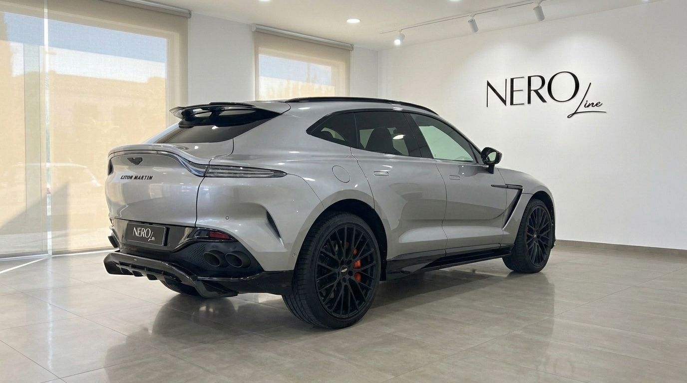 The metallic silver Aston Martin DBX707 is showcased from a rear three-quarter angle in a bright showroom in Madrid.