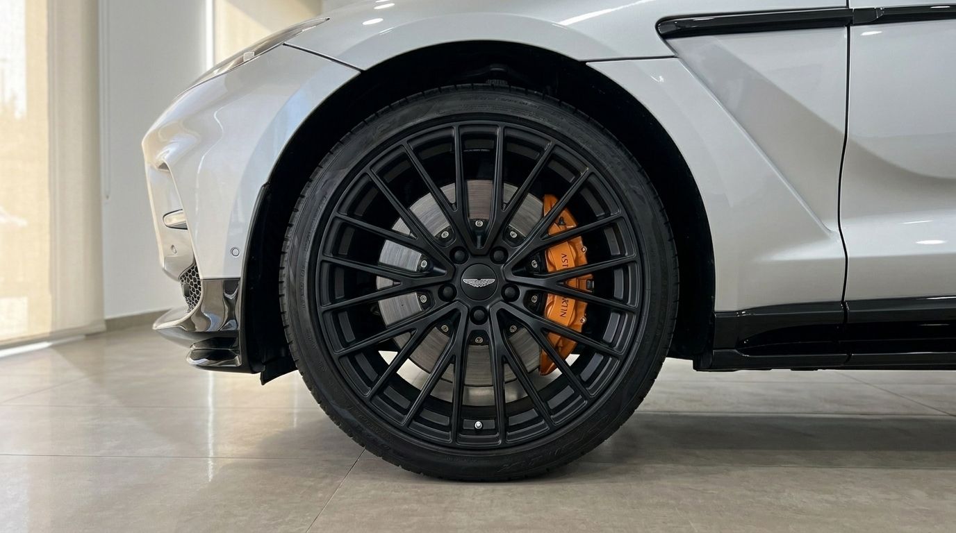 Close-up of the Aston Martin DBX707's front wheel with black multi-spoke rim and orange brake caliper, available for rent in Madrid.