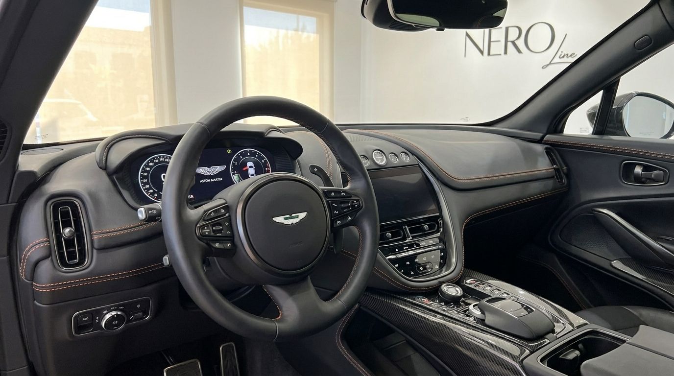 The luxurious cockpit and dashboard of the Aston Martin DBX707, featuring a steering wheel and infotainment system, available for rental in Madrid.