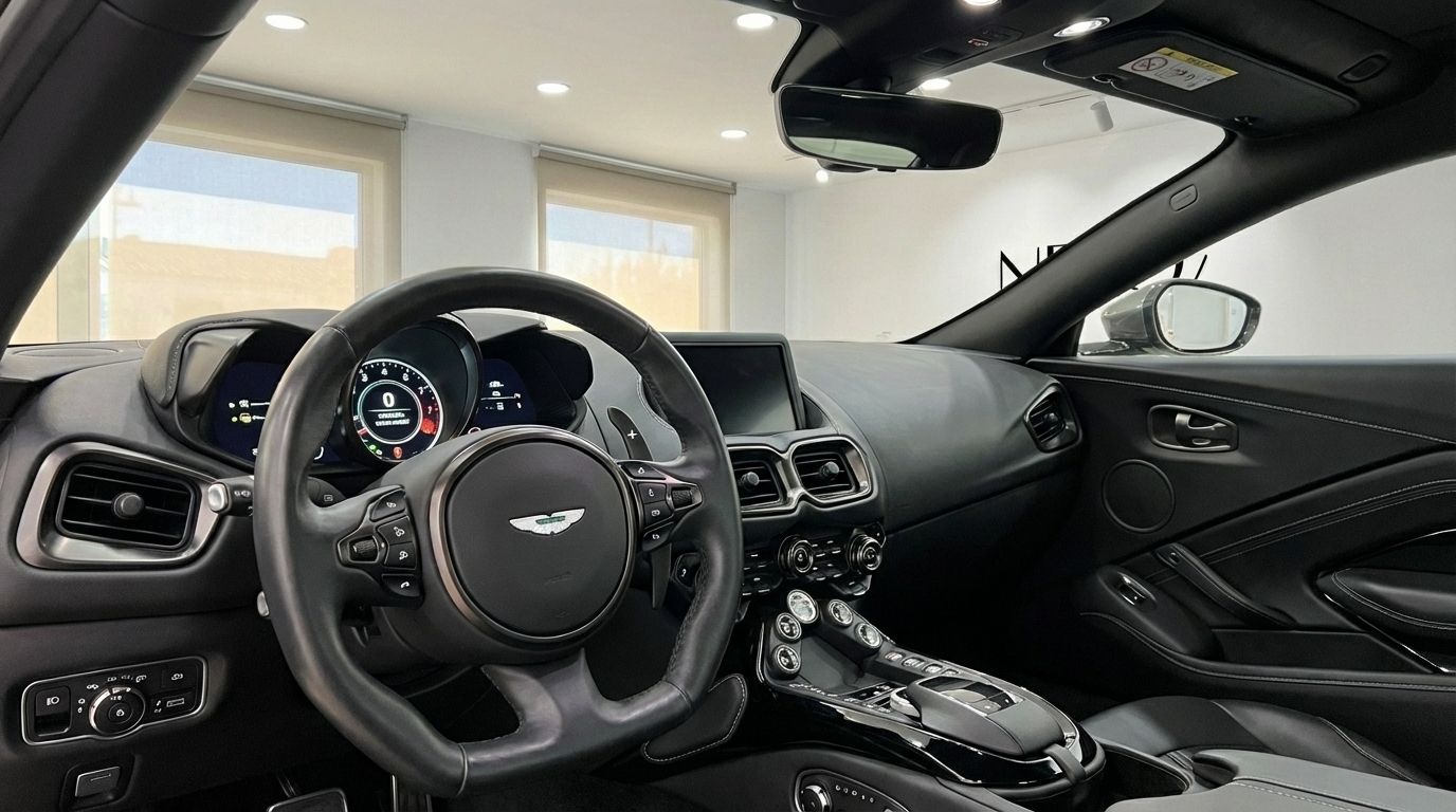 The luxurious black interior of the Aston Martin Vantage V8, showcasing the steering wheel, digital dashboard, and central console in Marbella.
