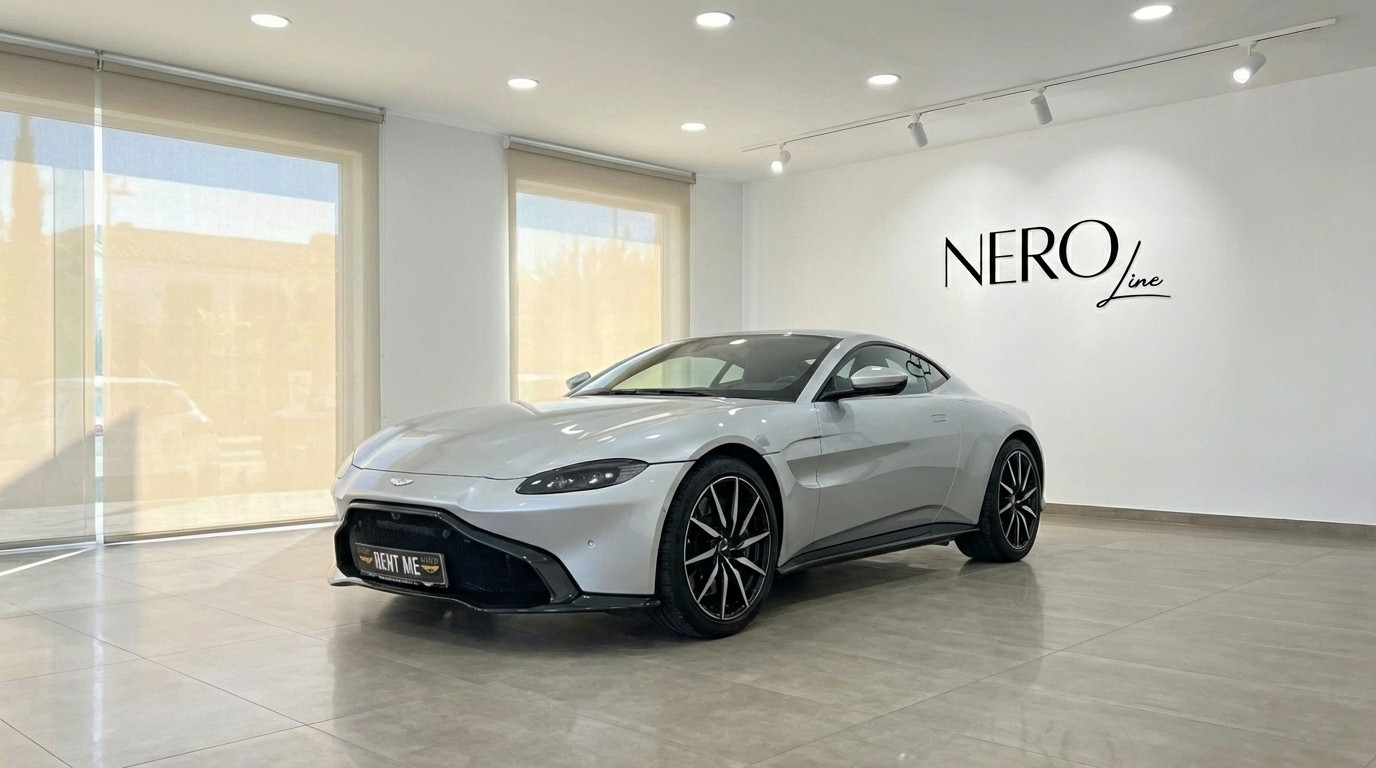Aston Martin Vantage V8 — Showroom in Marbella A silver-grey 2019 Aston Martin Vantage V8 is showcased from a front three-quarter view in a bright Marbella showroom.