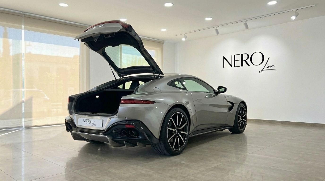 The silver grey Aston Martin Vantage V8 is showcased from a rear three-quarter angle with its trunk open in a Marbella showroom.