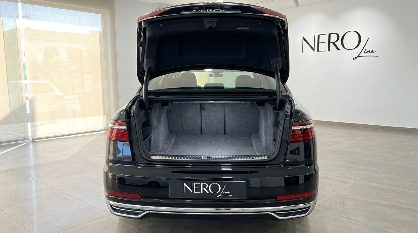 The rear view of the black Audi A8 L with its spacious trunk open, parked in a showroom in Alicante.