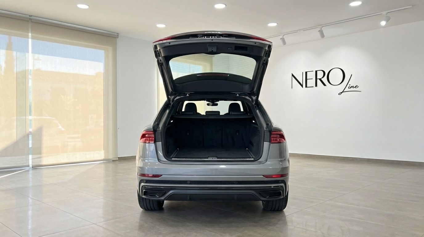 The matte gray Audi Q8 TDI is shown from the rear with its trunk open, highlighting the spacious cargo area in Alicante.