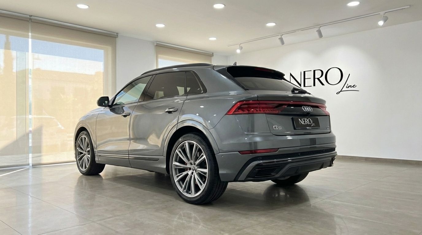 The matte gray 2023 Audi Q8 TDI is showcased from a rear three-quarter angle in a bright showroom in Alicante.