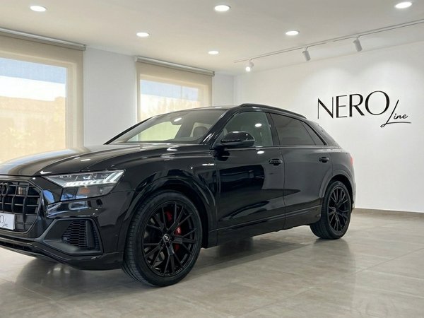 Audi Q8 S-line — SUV Premium en Showroom de Marbella El elegante Audi Q8 S-line negro se exhibe en ángulo frontal tres cuartos en un luminoso showroom de Nero Line en Marbella.