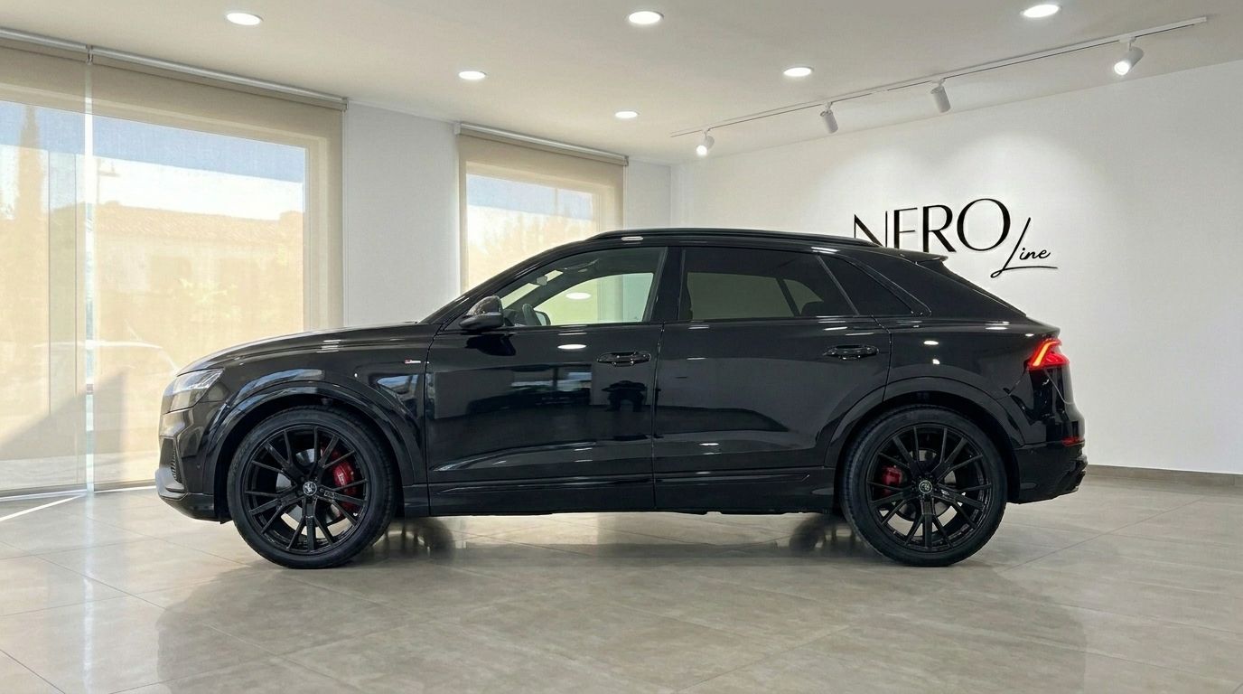El elegante SUV de lujo Audi Q8 S-line negro de 2021 está estacionado en el interior, mostrando su perfil y pinzas de freno rojas en Marbella.
