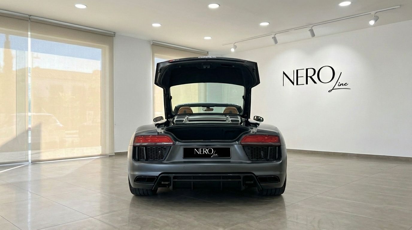 El Audi R8 Spyder gris oscuro mate se ve desde la parte trasera con el maletero abierto en un concesionario de Marbella.