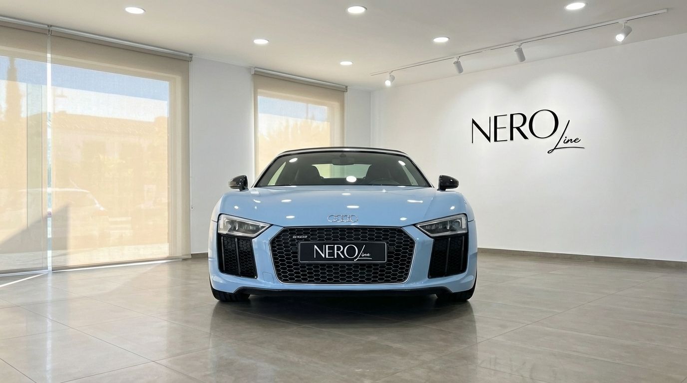 El Audi R8 Spyder descapotable azul claro se exhibe de frente en un moderno concesionario en Madrid.