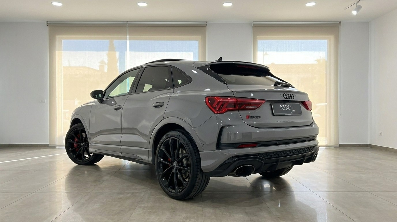 The 2022 Audi RS Q3 in gloss Nardo Grey is shown from a rear three-quarter angle in a showroom in Marbella.