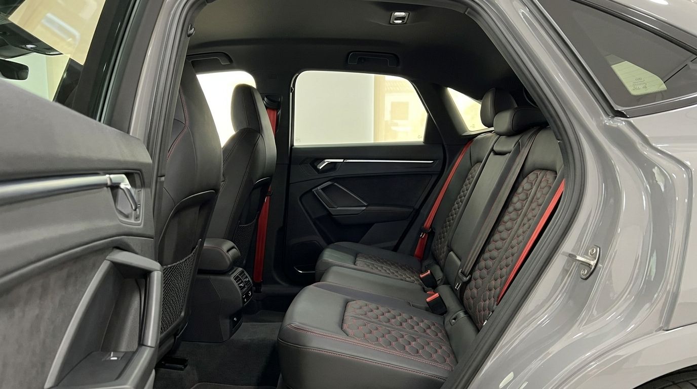 The luxurious rear interior of the Audi RS Q3 in Marbella, featuring black leather seats with red honeycomb stitching and matching seatbelts.