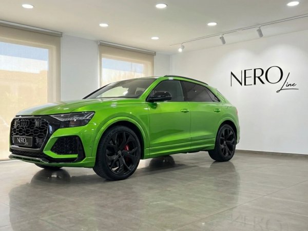 Audi RS Q8 — SUV Verde Neón en Showroom Madrid El Audi RS Q8 verde neón, un SUV de lujo y alto rendimiento, se exhibe prominentemente en un moderno concesionario de Madrid.