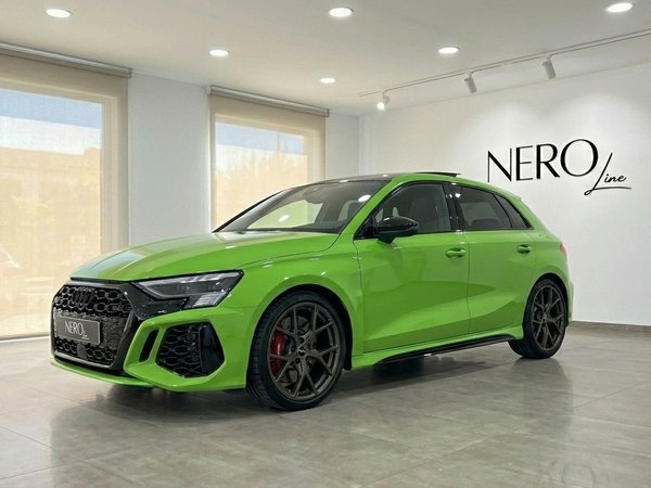 Audi RS3 Sportback — Vue avant à Marbella L'Audi RS3 Sportback 2023 vert Kyalami brillant est présentée de trois quarts avant dans un showroom à Marbella.