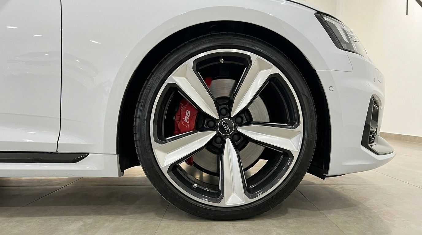 The front wheel of the white Audi RS5 in Alicante, featuring a black and silver rim and a red RS brake caliper.
