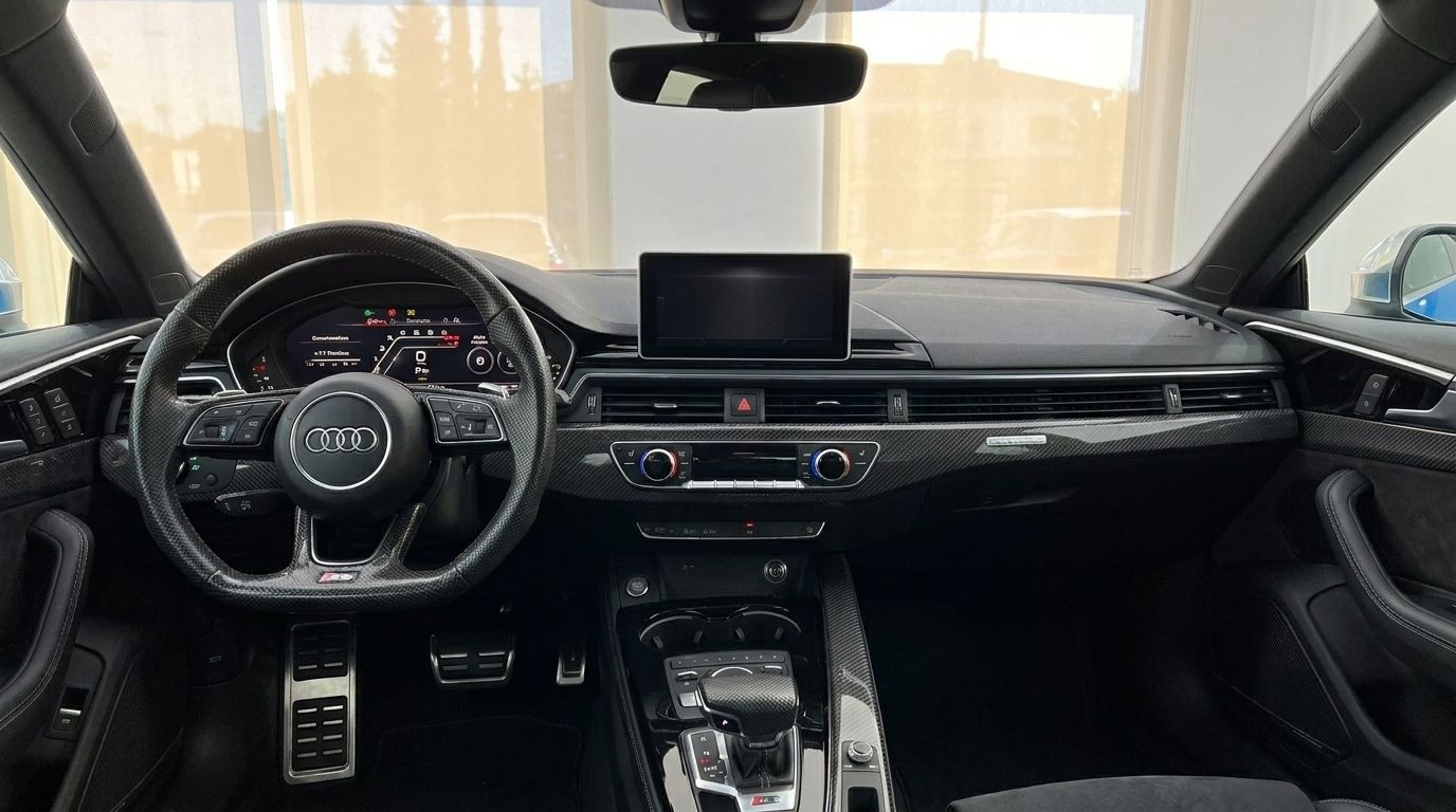 The luxurious interior dashboard and steering wheel of the 2020 Audi RS5, featuring carbon fiber accents, in Alicante.