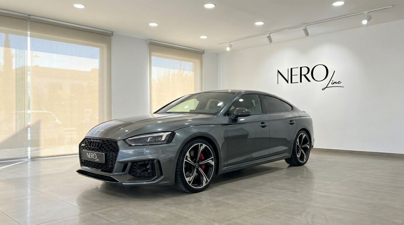 The metallic Daytona Gray Audi RS5 Sportback is showcased from a front three-quarter angle in a bright showroom in Benidorm.