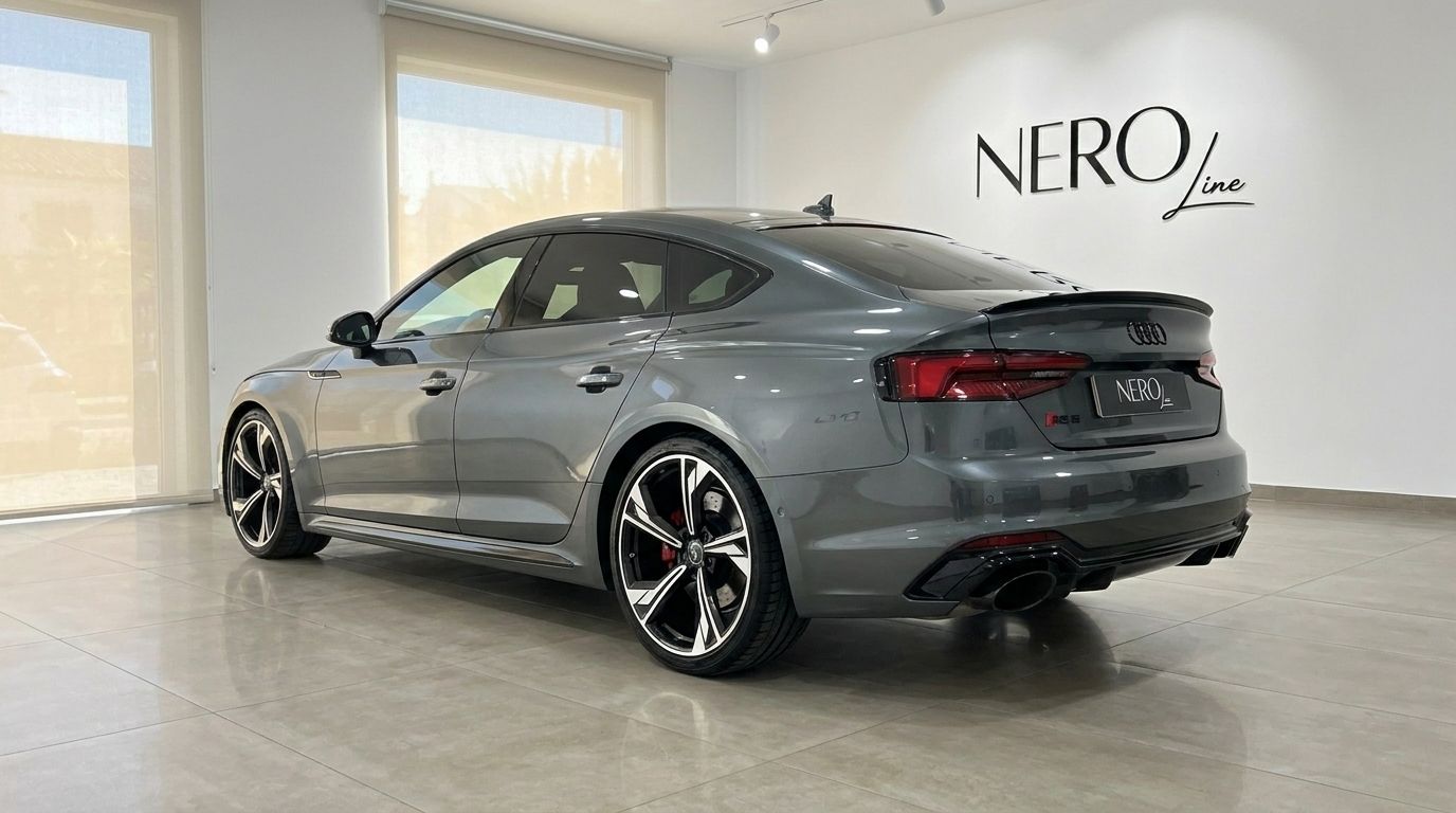 The metallic Daytona Gray Audi RS5 Sportback is showcased from a rear three-quarter view, parked on a polished floor in a Benidorm showroom.