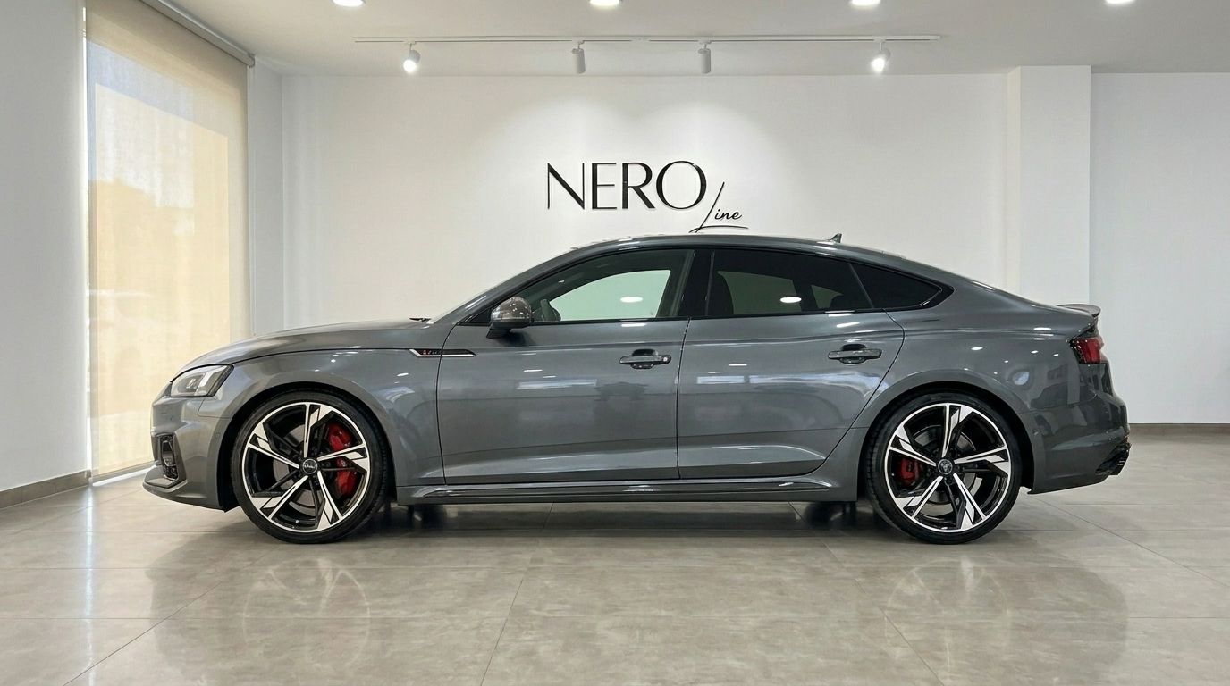 The metallic Daytona Gray Audi RS5 Sportback is shown from its side profile, parked in a bright showroom in Benidorm.