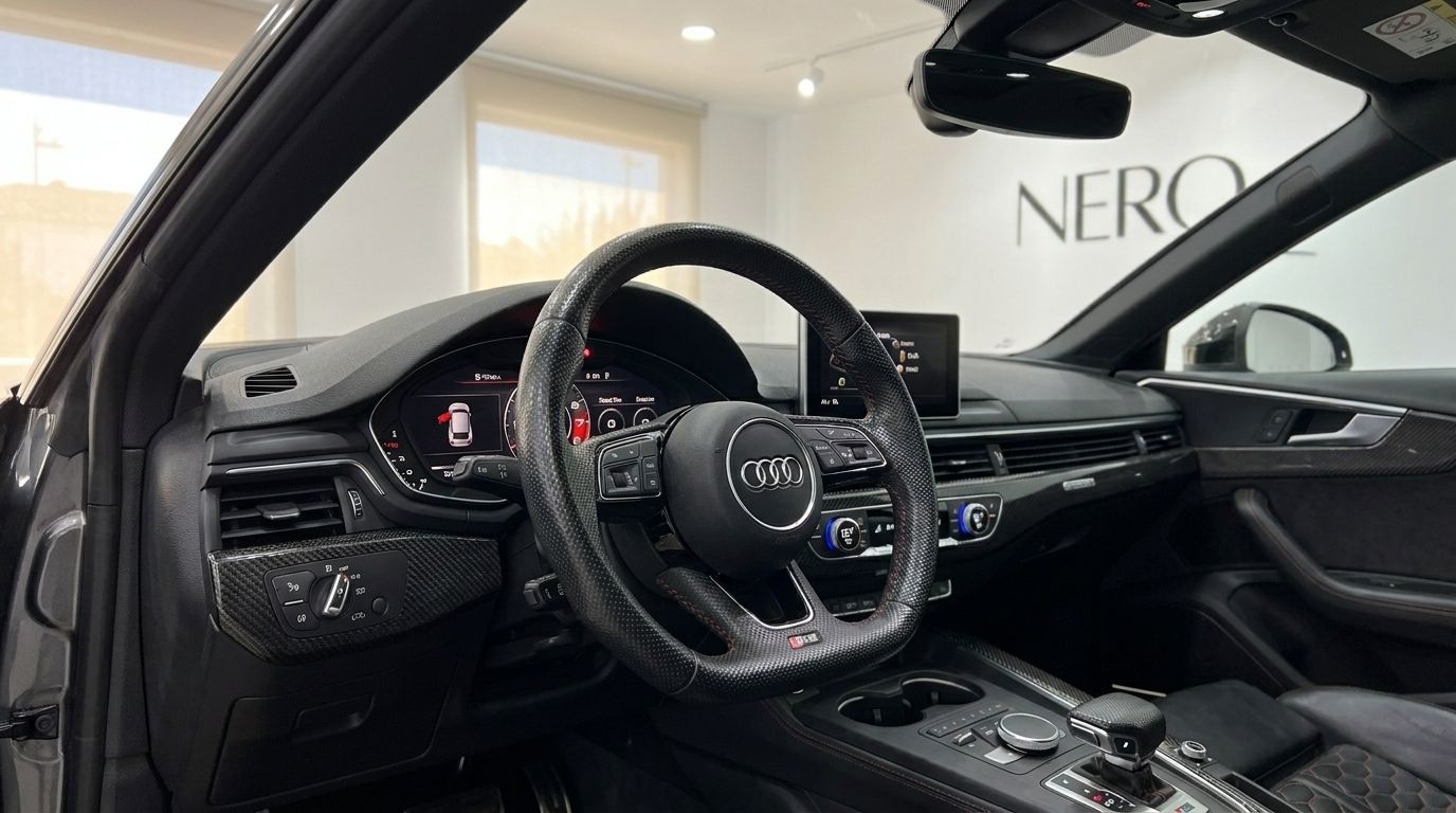 The luxurious interior of the Audi RS5 Sportback in Benidorm, showcasing the steering wheel, dashboard, and carbon fiber trim.