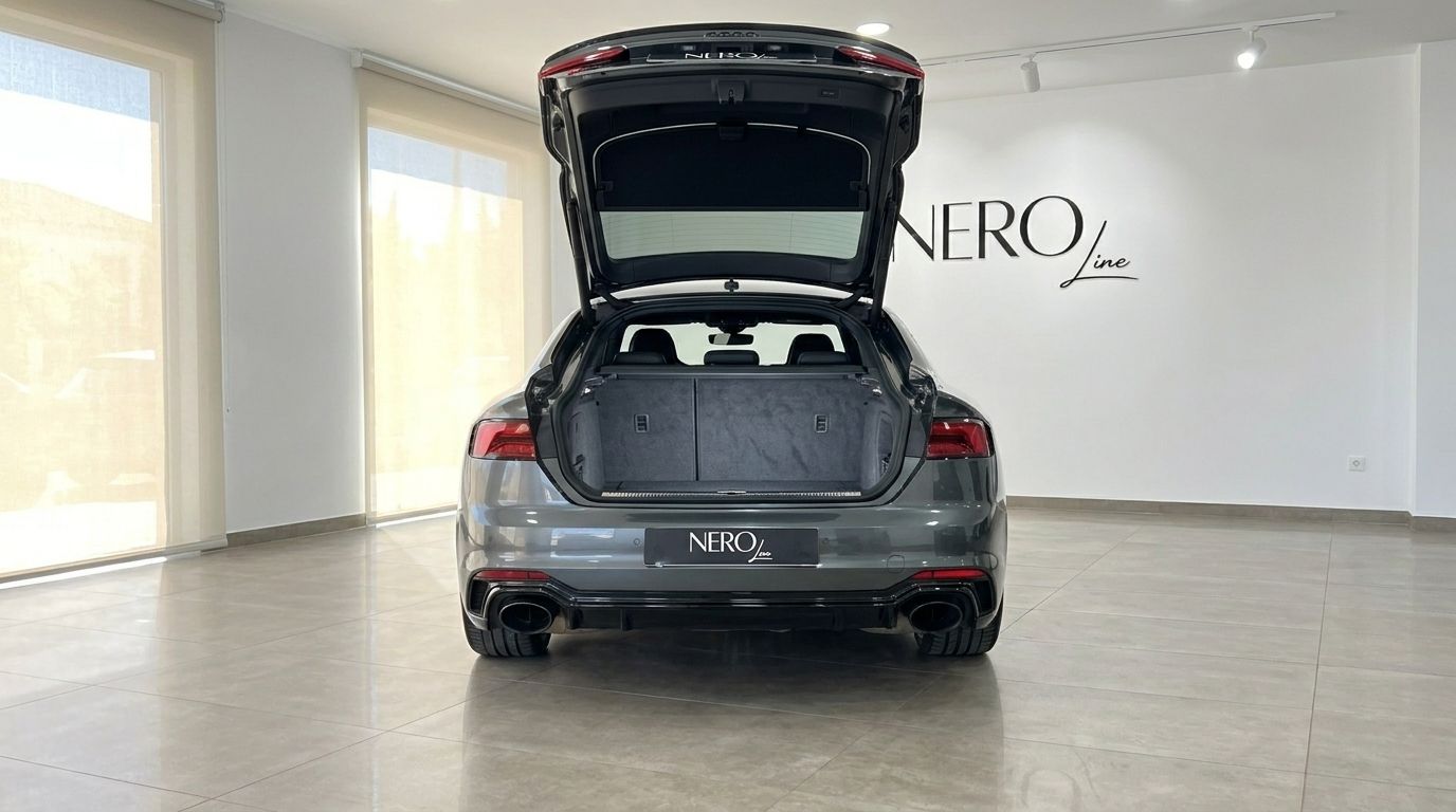 The metallic Daytona Gray Audi RS5 Sportback is shown from the rear with its trunk open, revealing ample cargo space in Benidorm.