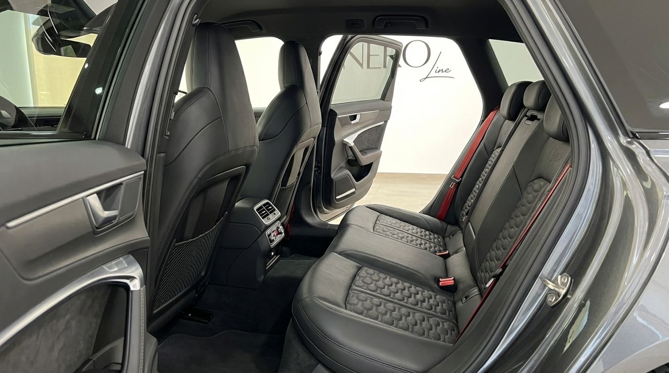 The Audi RS6 Avant's luxurious rear interior features black leather seats with honeycomb stitching and distinctive red seatbelts in Marbella.