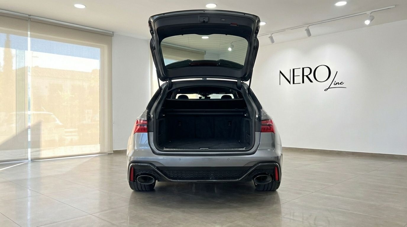 The matte gray Audi RS6 Avant is seen from the rear with its spacious trunk open in a bright Marbella showroom.