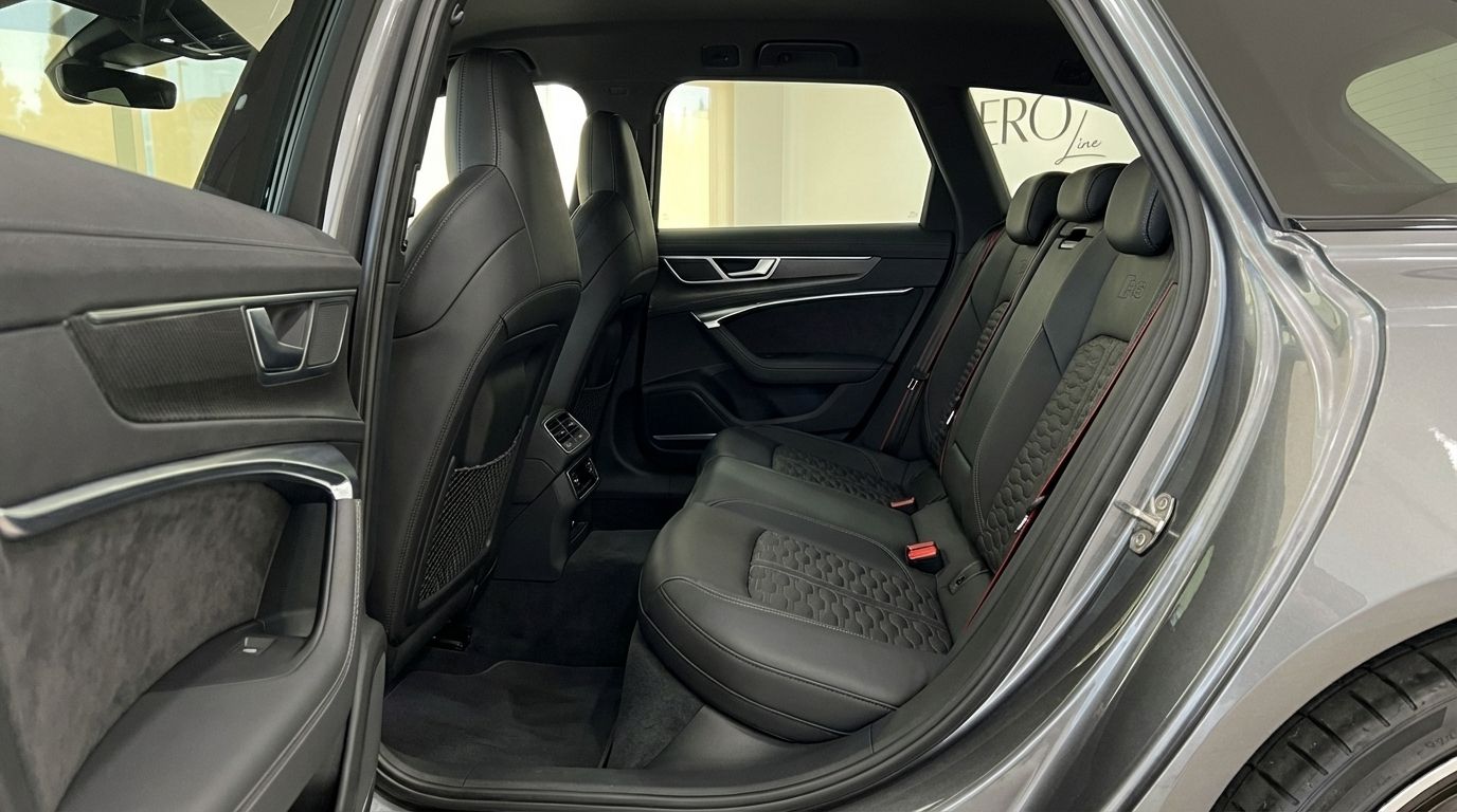 The rear interior of the Audi RS6 Performance in Marbella, showcasing its black leather seats with honeycomb stitching and open door.