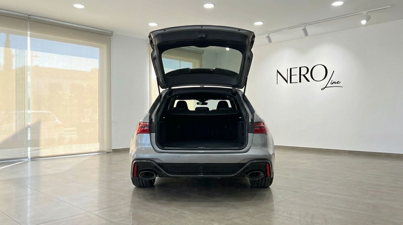 The metallic gray 2025 Audi RS6 Performance is shown from the rear with its trunk open, parked in a showroom in Marbella.