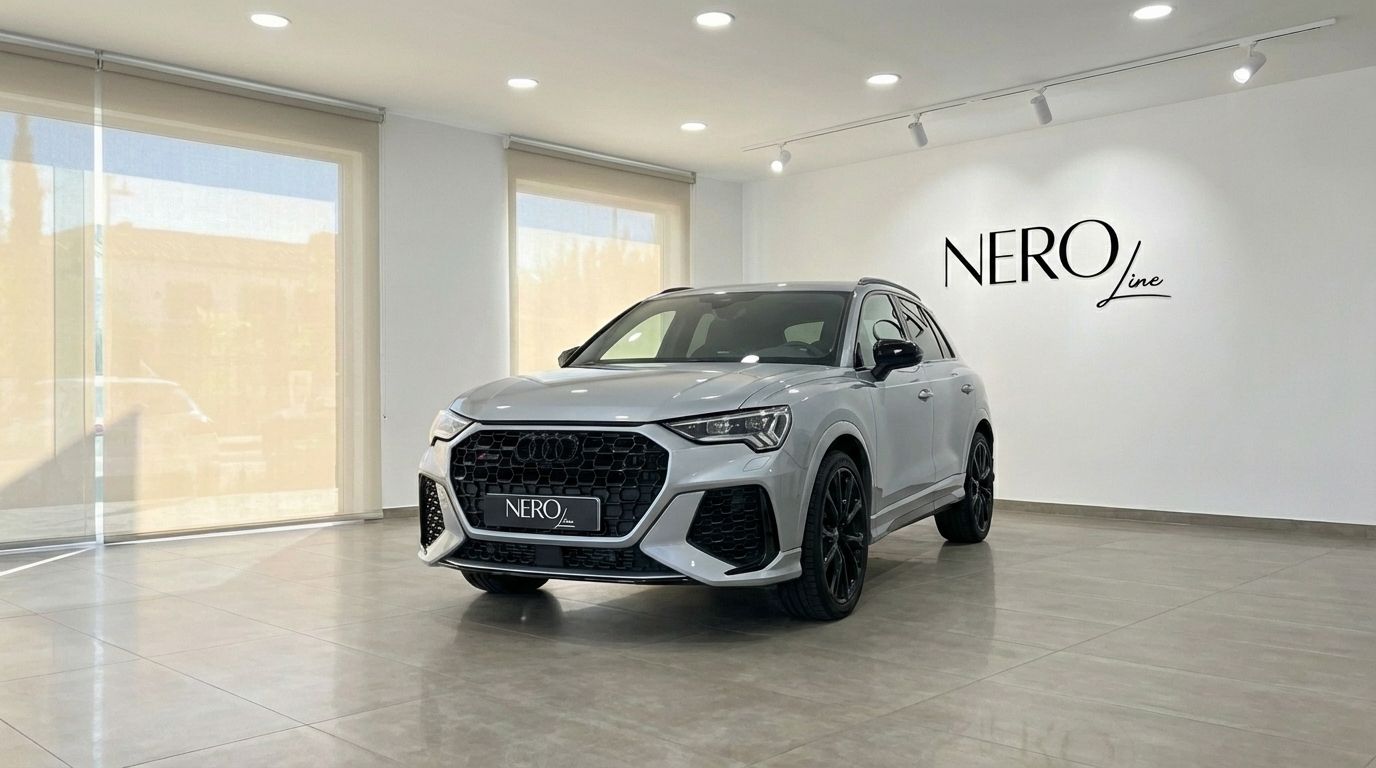 The metallic silver Audi RSQ3 is showcased from a front view in a bright showroom in Barcelona.