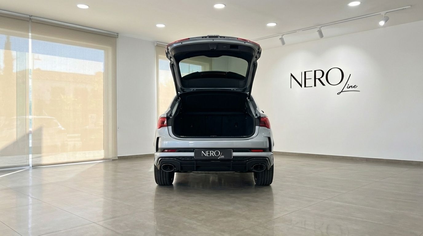 The rear view of a metallic silver Audi RSQ3 with its trunk open, parked in a showroom in Barcelona.