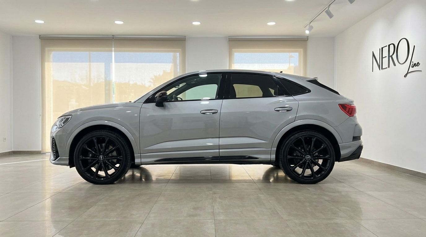 The metallic silver 2023 Audi RSQ3 is seen from its side profile, parked on a tiled floor in a bright Barcelona showroom.
