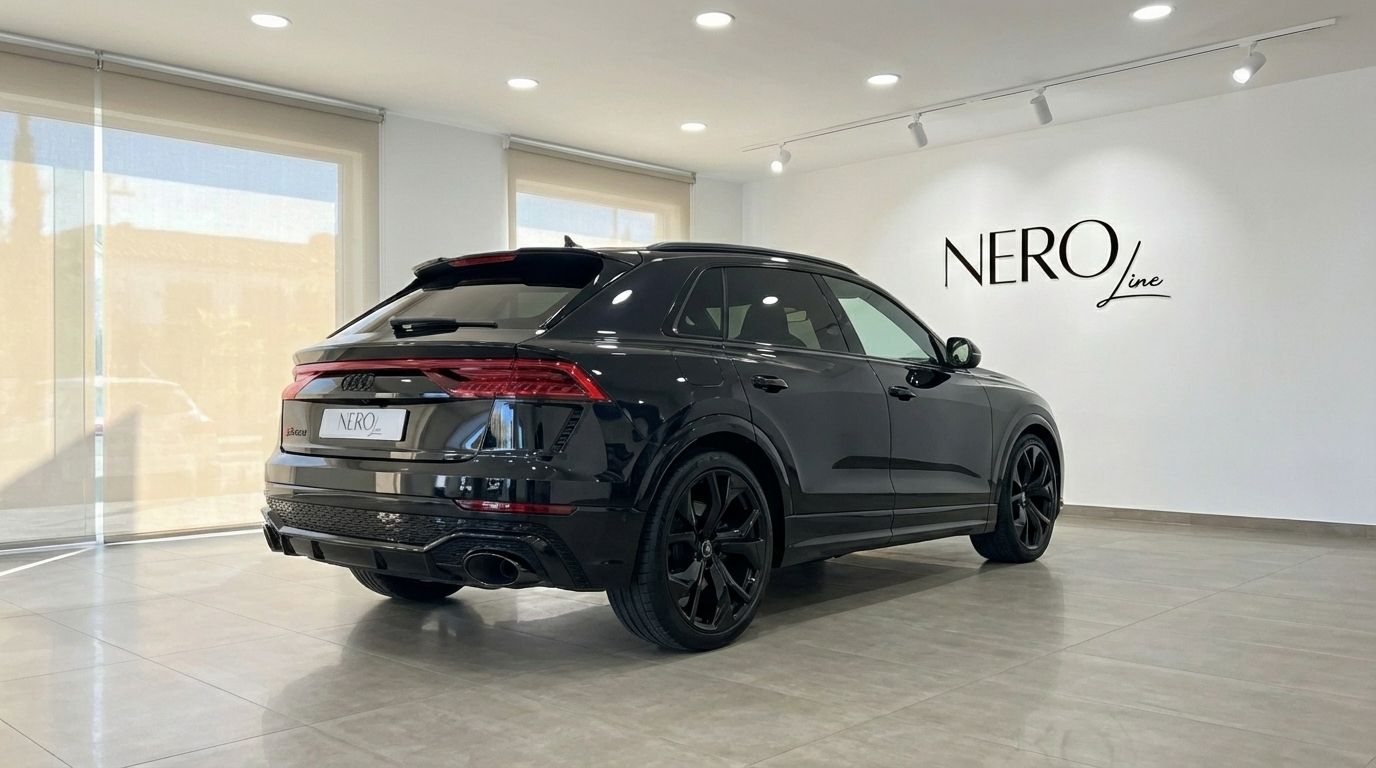 El Audi RSQ8 negro 2025 se muestra desde una vista trasera tres cuartos, destacando su diseño elegante y llantas negras en un concesionario de Madrid.