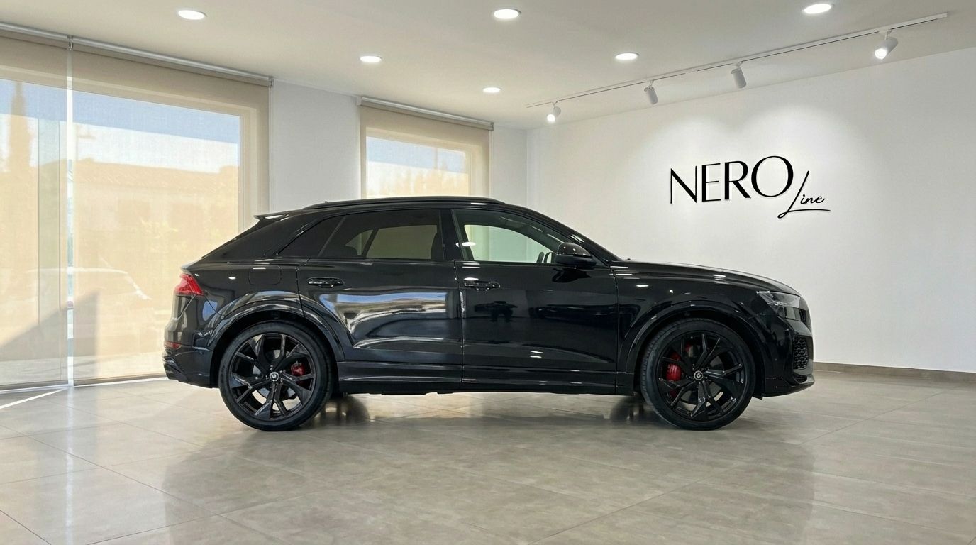 El SUV de lujo Audi RSQ8 negro 2025 se exhibe en un concesionario de Madrid, visto desde su elegante perfil lateral.