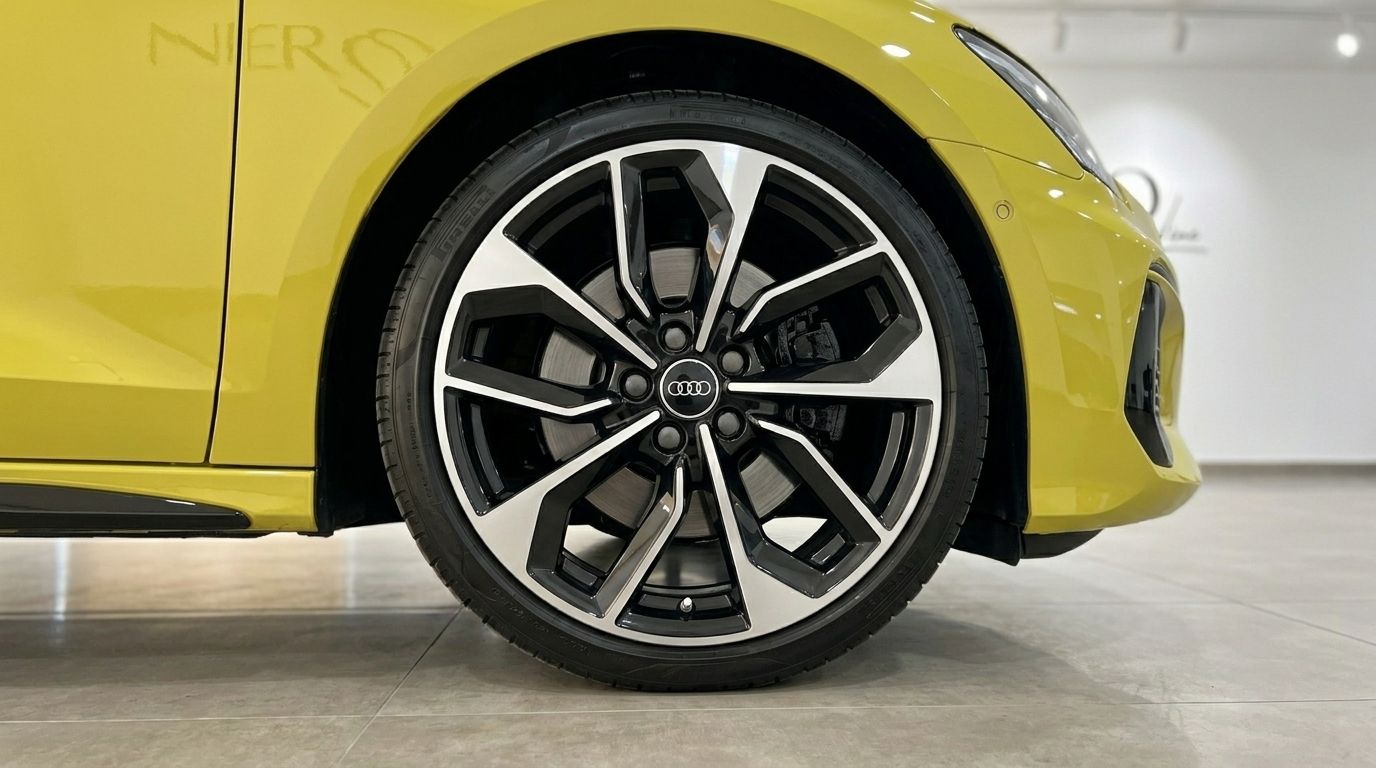 Close-up of the gloss Python Yellow Audi S3's front wheel, showcasing its black and silver multi-spoke rim in Alicante.