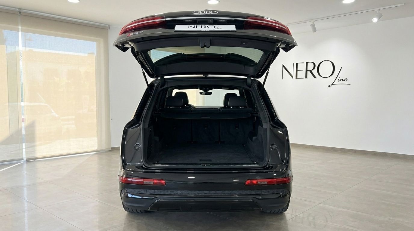 L'Audi SQ7 noire est montrée de l'arrière avec son coffre ouvert, révélant la zone de chargement spacieuse dans un showroom de Marbella.