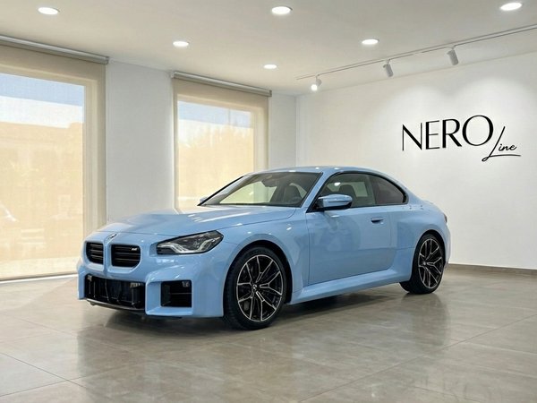 BMW M2 Competition — Front three-quarter view Alicante A light blue BMW M2 Competition, 2025 model, is parked in a showroom in Alicante, showing its front three-quarter view.