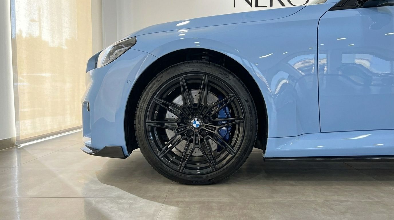 Close-up of the light blue BMW M2 Competition's front wheel with black rim and blue brake caliper in Alicante.