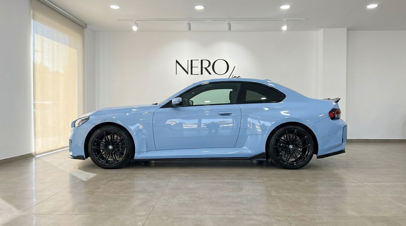 The light blue BMW M2 Competition is showcased from its side profile in a bright showroom in Alicante.