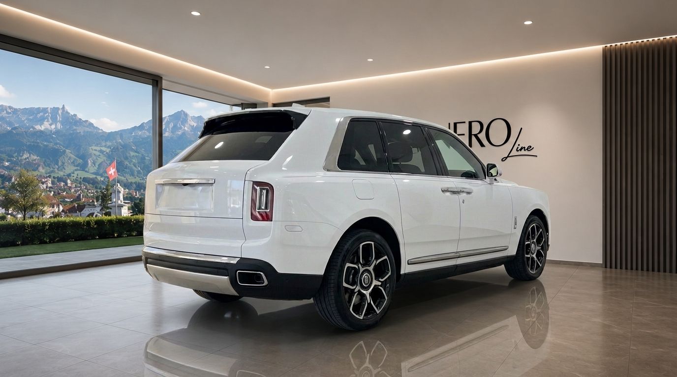 The white Rolls Royce Cullinan is parked in a showroom, showcasing its rear three-quarter view with Swiss mountains in the background.
